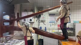 Two women ride noodle sheeting machine to cook large dough in Shanxi, China