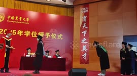 Student and university president have fun with bubbles at graduation