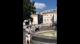 Woman collects coins from the Fountain in Trafalgar Square, London, England, UK