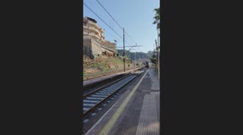 Train with flashing headlights arrives at Ali Terme station in Sicily, Italy
