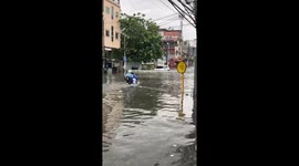 Optimistic scooter rider braves waist deep floods on road