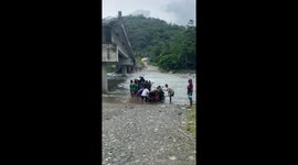 Locals carry motorcycles through surging river