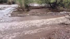 Floodwaters flow like a river after rain in driveway in Pinal, Arizona