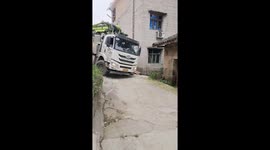 Truck hits roof while struggling on narrow downhill curve in Chongqing, China