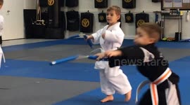 A group of funny kids training to use nunchucks in a karate class