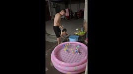 Father gently swings child toward kiddie pool to pick up toys in Henan, China