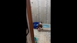 Little boy lies beside basin and plays with running water in Bekasi, Java, Indonesia