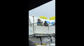 Airport ground worker greets passengers with a smile through the pouring rain