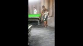 Father plays billiards with sleeping baby on his back in Guizhou, China