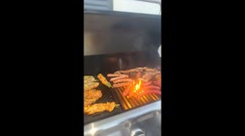 Grilled sausage squirts like a fountain in barbecue scene in Marseille, France