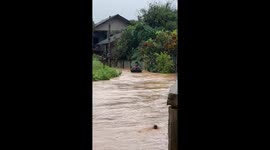 Resident uses umbrella and basin to float through floods