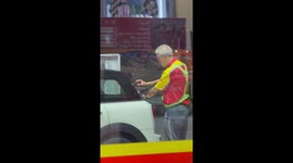 Kind grandfather cleans car's windows at petrol station