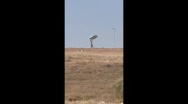 Man struggles with umbrella in windy desert field in Monegros, Aragon, Spain