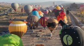 Hot air balloons in various shapes soar over Cappadocia at sunrise