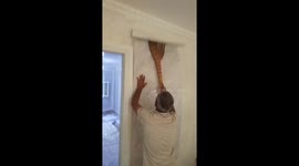 Man struggles to hang wallpaper using broom in Mingachevir, Azerbaijan