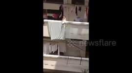 Child sitting on edge of balcony rescued by brother