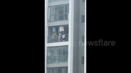 Young children dangle from 13-floor balcony in terrifying scene