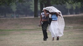 Sunseekers attempt to shelter as heatwave breaks with thunderstorm in Greenwich Park, South East London
