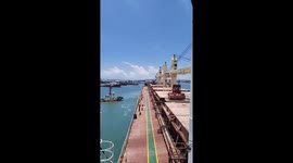 Tug boat pulls dry bulk carrier out of port