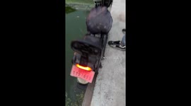 Man struggles as e-bike barely holds its ground near water in Shandong, China