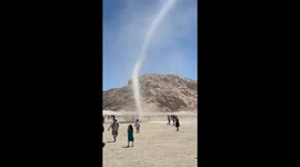 Dust devil tornado winds through tourists in desert