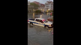 Police car push stalled car out of floodwaters in Ocean City, Maryland, USA