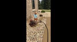 Toddler Watering his Baby Brother