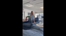 An energetic 4-year-old girl jumps off a lounge chair and takes a comical tumble.