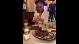 Friend struggles to cut steak on a shaky table in New York, USA