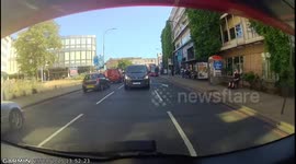 Pedestrians crossing in front of ambulance on blue lights and sirens.