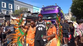 Notting Hill Carnival 2025 - hot male dancers in orange costumes entertain crowds in Westbourne Grove