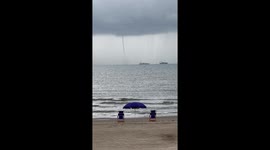 Pelicans Dive Into Ocean in Front of Towering Waterspout