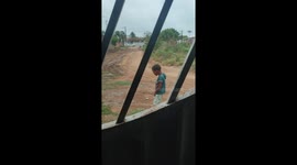 Child playfully mimics rooster in Feira de Santana, Bahia