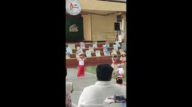 Little boy attempts to put on a young girl’s slippers at a school program