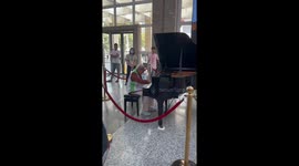 Elderly woman plays grand piano in hospital lobby