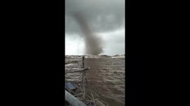Terrifying dust devil tornado rips up sand along coastline