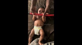 Baby pretends to lift weight with uncle in Gibsonton, Florida