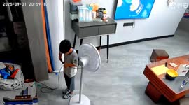 Young boy cuts live fan power cord with scissors sending sparks flying