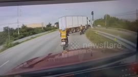 Motorcycle rider survives being hit by truck as it overturns onto spot where she is waiting