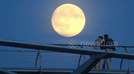 The September Full Moon, known as the Corn Moon seen rising in the skies of London as people watch from the Millennium Bridge