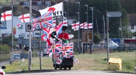Kent man parades mobility scooter tank along flag-lined street, UK