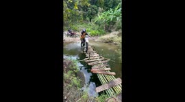 Off-road motorbike rider tumbles into pond while crossing bamboo bridge