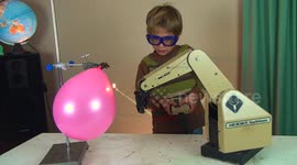 Young boy pops balloon with robotic arm