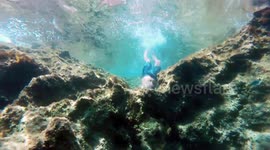 Man swims through a tiny hole underwater