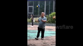 Elderly man spins diabolos with head and hands