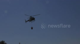 Israel: Hovering fire fighting police helicopter with bambi bucket scoops water pool during drill
