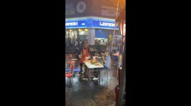 Man enjoys drink in the rain at night market in Liaoning, China
