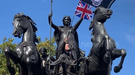 A protestor climbs on a statue of Queen Boudica during a far right wing rally in London