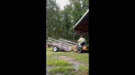 Man struggles to load lawn mower onto trailer in Smithfield, Virginia, USA