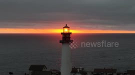 US: A lighthouse stands silhouetted against a red-hued sunset